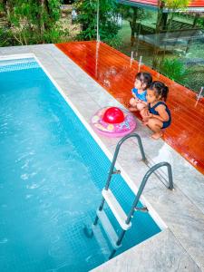 two children sitting next to a swimming pool at Pang Long Chao resort in Trang