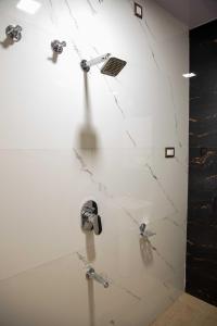 a bathroom with white marble walls and a shower at PVR Suites off Bannerghatta Road in Bangalore