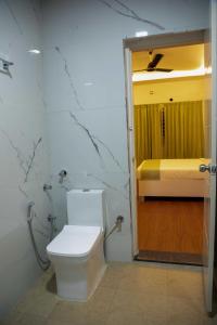 a bathroom with a toilet and a bed in a room at PVR Suites off Bannerghatta Road in Bengaluru