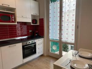 a kitchen with white cabinets and a window with a microwave at Etrusco Viola - Appartamento "Giglio Viola" in Bagno a Ripoli