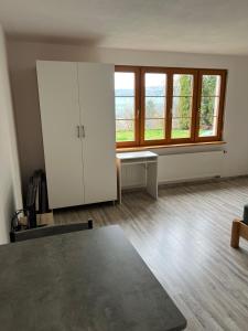 een lege kamer met een tafel en een aantal ramen bij Kleine Ferienwohnung - Nähe Schweizergrenze in Hohentengen