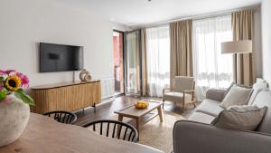 a living room with a couch and a table with a tv at Lion Apartments - SCALA City Center Apartments&Parking H in Gdańsk