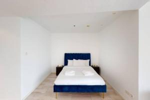 a bed with a blue headboard in a white room at Breathtaking Studio - Al Jaddaf in Dubai