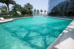 a large pool of blue water with palm trees and a building at Breathtaking Studio - Al Jaddaf in Dubai
