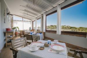a dining room with tables and chairs and windows at B&B Le Ginestre in Portoscuso