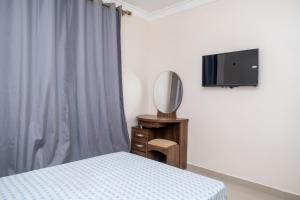 a bedroom with a bed and a mirror and a tv at Casa Chico Rosa in Luanda