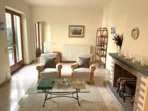 sala de estar con 2 sillas y chimenea en Villa Giardino, en Forte dei Marmi