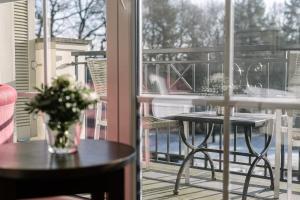 eine Vase mit Blumen auf einem Tisch auf einem Balkon in der Unterkunft Parkhotel Surenburg in Hörstel