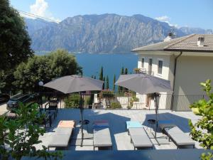 a pool with chairs and umbrellas with a view of a lake at Finestra sul Lago Malcesine Apt Riva in Malcesine