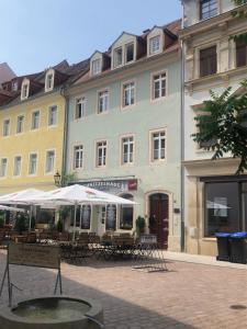 a building with tables and umbrellas in front of it at Ferienwohnung Am Theaterplatz in Meißen