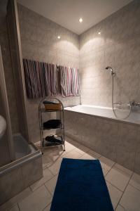 bagno con vasca, doccia e tappeto blu di Rohrmoser Appartements a Sankt Johann im Pongau