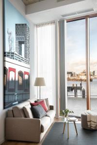 a living room with a couch and a large window at Eric Vökel Boutique Apartments - Riverfront Suites in Amsterdam