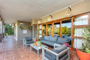 uma sala de estar com um sofá, cadeiras e janelas em Die Fonteine Country Guest House em Oudtshoorn