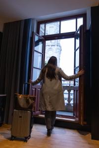 ポルトにあるAxis Porto Club Aliadosの窓をスーツケースを持って歩く女性