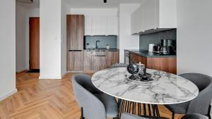 a kitchen with a marble table and chairs at Lion Apartments - Riverside Nadmotławie - Sauna, Gym & Kids Play in Gdańsk