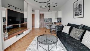 a living room with a black couch and a table at Lion Apartments - Riverside Nadmotławie - Sauna, Gym & Kids Play in Gdańsk