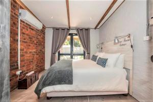 a bedroom with a large bed and a brick wall at Wine Route Cottages in Simondium