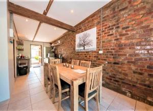 uma sala de jantar com uma parede de tijolos e uma mesa de madeira em Wine Route Cottages em Simondium