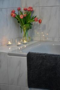 a vase of red tulips in a bathroom with lights at Heimathafen Langballigholz in Langballigholz