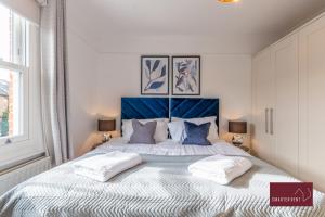 a bedroom with a large bed with two pillows at 3 Bed Victorian House - Kingston On Thames in Kingston upon Thames