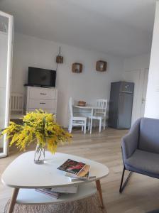 een woonkamer met een vaas met bloemen op een salontafel bij Joli appartement avec jardin dans résidence avec piscines in Agay - Saint Raphael