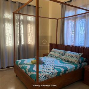 a bedroom with a four poster bed with a canopy at E&E Holiday Apartment in Dar es Salaam