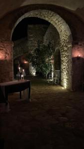um quarto escuro com uma mesa e um arco de pedra em Barone Gambadoro em Monte SantʼAngelo