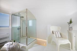 La salle de bains est pourvue d'une douche en verre et d'une chaise blanche. dans l'établissement DAY DREAM 2, à Oia