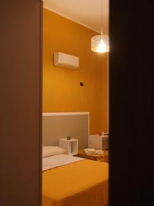 um quarto com uma cama e uma parede amarela em Villa Flora em Pompeia