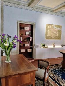 wazon kwiatów na drewnianym stole w pokoju w obiekcie Foresteria San Niccolò w mieście Prato