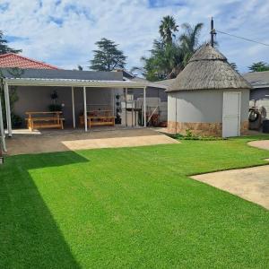 a house with a grass yard in front of it at Rosies Inn in Piet Retief