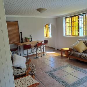 a living room with a table and chairs and windows at Rosies Inn in Piet Retief