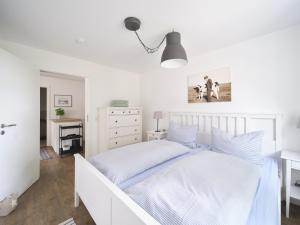 a bedroom with a white bed and a white dresser at Hof Maiholm - Sattelkammer in Medelby
