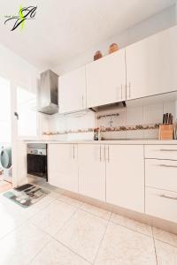 a white kitchen with white cabinets and a window at Tenerife Homestay in San Miguel de Abona