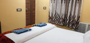 een slaapkamer met een wit bed en een raam bij Hotel Eleven in Bhagalpur