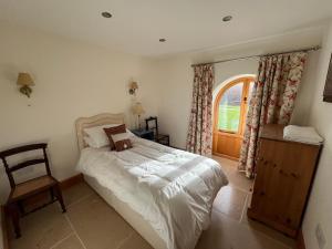 a bedroom with a bed and a chair and a window at Shircombe Lodge - Exmoor National Park in Dulverton