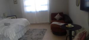 1 dormitorio con 1 cama, 1 silla y 1 mesa en Real Touch Body Spa Accomodation, en Mthatha