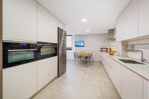 a kitchen with white cabinets and a table in it at NEW Seaview Ap Anita by JS Villas in Port de Pollensa