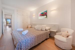 a white bedroom with a bed and a chair at NEW Seaview Ap Anita by JS Villas in Port de Pollensa