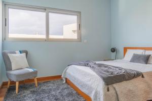 1 dormitorio con 1 cama, 1 silla y 1 ventana en Casa verde, en Ribeira Grande