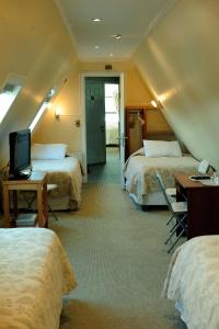 a hotel room with three beds and a tv at Hotel Seminario in Puerto Montt