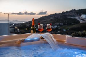 zwei Flaschen und zwei Gläser Wein in einem Whirlpool in der Unterkunft Pleiades Villas Naxos2 (Hottub) in Agkidia