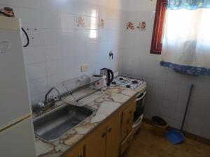 a kitchen with a sink and a stove at Departamentos Familiares Rosas Rojas in Villa Gesell