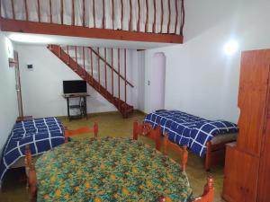 a room with two beds and a table and a staircase at Departamentos Familiares Rosas Rojas in Villa Gesell