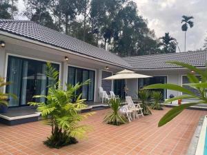 ein Haus mit einer Terrasse mit Stühlen und einem Sonnenschirm in der Unterkunft Pool Villa Nita in Ban Na Klang