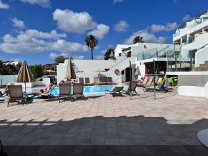 a pool with chairs and umbrellas next to a building at Apartamentos Villa Canaima in Puerto del Carmen