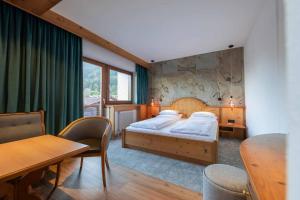 sypialnia z łóżkiem, stołem i krzesłami w obiekcie Familien- & Vitalhotel Auenhof w mieście Fulpmes