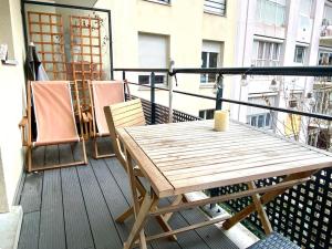 einen Holztisch und Stühle auf dem Balkon in der Unterkunft Grand appartement cosy avec balcon 6 personnes in Saint-Ouen