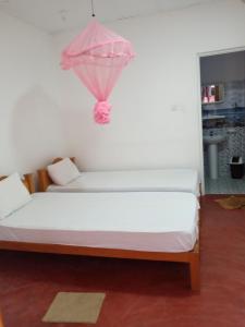 Un dormitorio con una cama con una sombrilla rosa. en U new guest house, en Nilaveli