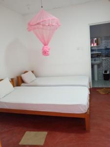 een slaapkamer met een bed met een roze paraplu erop bij U new guest house in Nilaveli